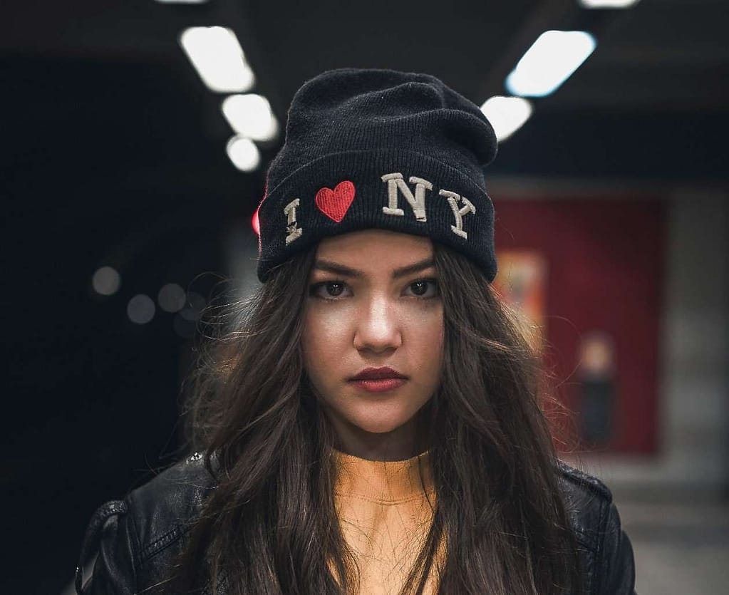 Girl in subway wearing an 'I Love New York' beanie cap.